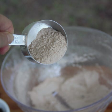 A one-third cup measure is being used to scoop out chocolate protein mix from the bulk bowl.