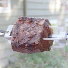 A cooked rib eye roast on an outdoor rotisserie.