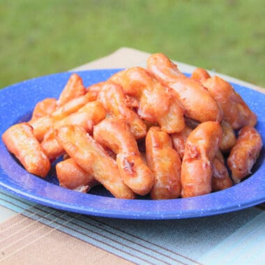 A blue camp plate is stacked with glazed apple fritters shaped like chips