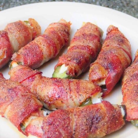 A white plate holds a pile of cooked bacon-wrapped jalapeno pepper atomic buffalo turds.