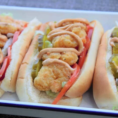 A close up shot of a finished Cajun shrimp po'boy on a white serving platter.