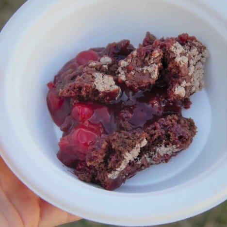 A white disposable bowl containing a serving of Cheerwine Cherry Cola Chocolate Dump Cake.