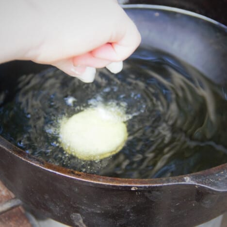 A deep fried Oreo being gently placed into a Dutch oven deep fryer.