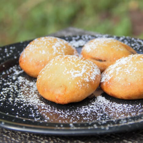 A black camp plate with four deep fried Oreos served dusted with powdered sugar.