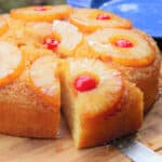 A slice of pineapple upside down cake is being removed with a knife.