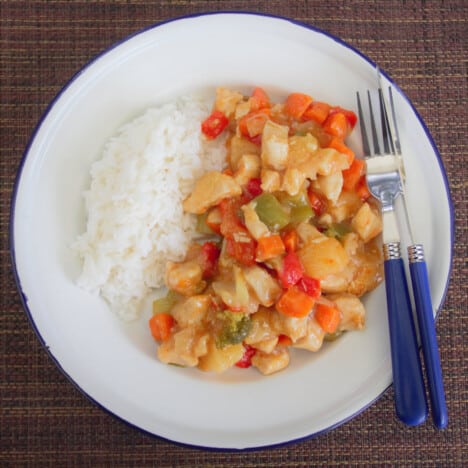 Looking down on a serving of sweet and sour chicken stew with a side of steamed rice.