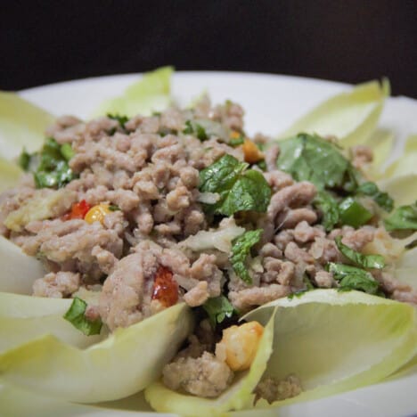 Multiple endive leaves filled with chicken larb ready to be served as a finger food.