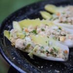 A row of endive leaves filled with Thai chicken salad.