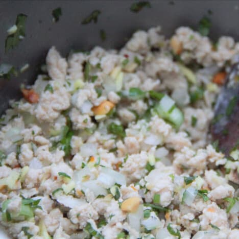 A completed chicken larb is sitting in the wok waiting to be divided among the endive leaves.
