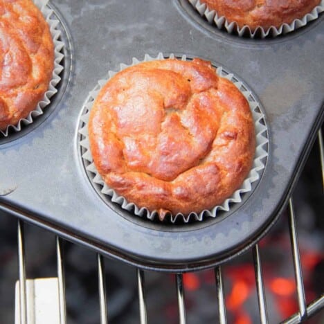 Close up of a breakfast bite in a muffin tray sitting on grill grates above burning coals.