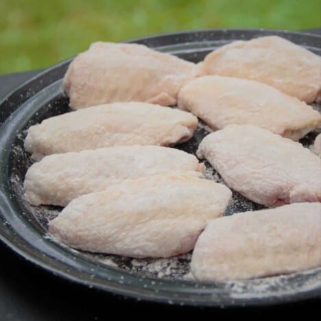A black camp plate filled with flour dusted chicken wings ready to be cooked.