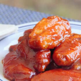 A served plate of chicken wings covered in a bird and glossy red buffalo sauce.