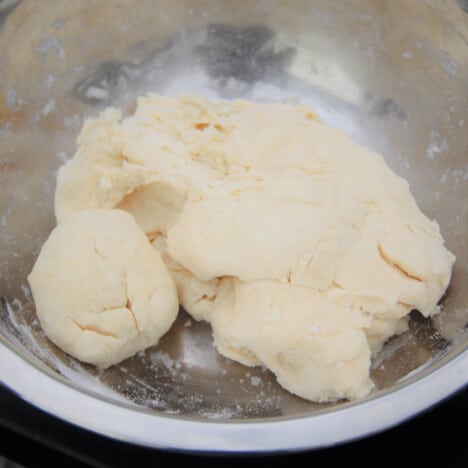 A rough dough to make dumplings sits in a stainless steel bowl.