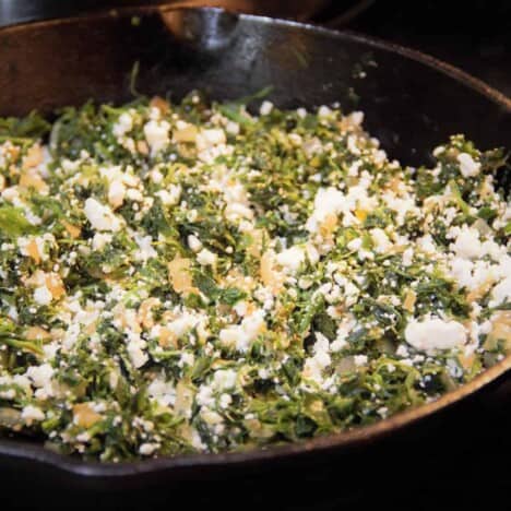 A skillet filled with spinach and feta filling.