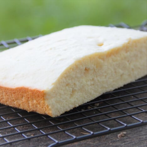 A half of the cooked biscuit cake base is cooling on a wire rack.