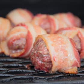 Close up of Cheese Stuffed Bacon Wrapped Meatballs sitting on a smoker rack