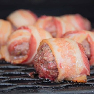 Close up of Cheese Stuffed Bacon Wrapped Meatballs sitting on a smoker rack.