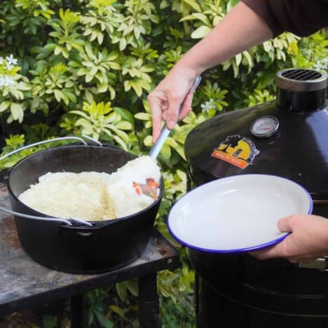 A caucasin arm is scooping a serving of shepherd's pie from a Dutch oven.