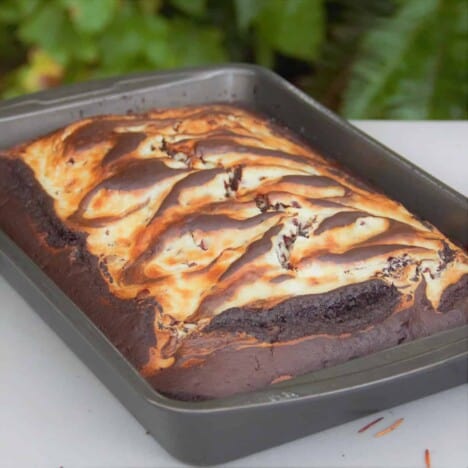A hot from the oven chocolate earthquake cake with a cream cheese swirl cooling in the cake tin on a white table.