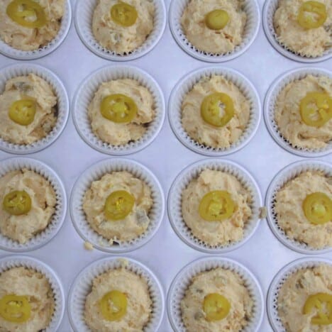 Looking down onto a muffin tin filled with jalapeno cornbread muffin batter.