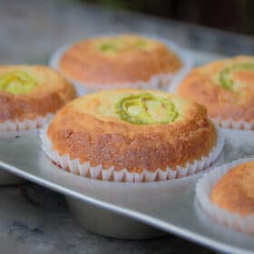 A close up shot of a golden brown jalapeno cornbread muffin in a muffin tin with a white paper liner.