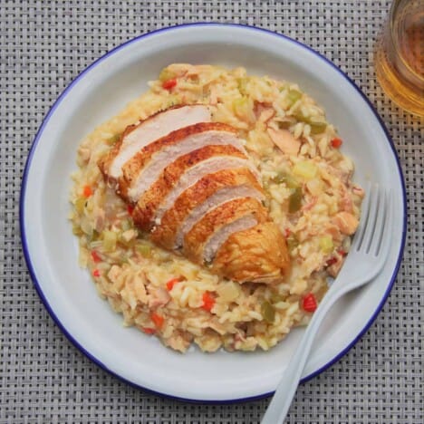 Looking down on a white plate with Cajun style smoked chicken risotto with a gray checkered table cloth.