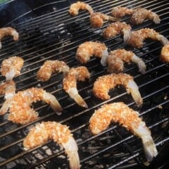 Several coconut encrusted shrimp are cooking on a hot grill.
