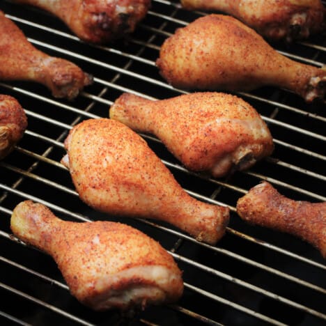 Looking at chicken drumsticks sitting on a grill grate.
