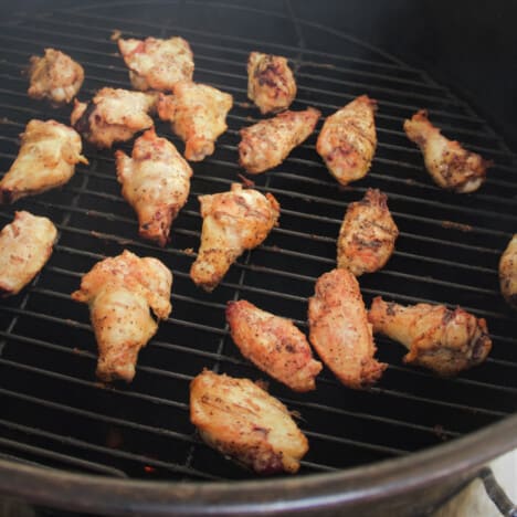 Looking across the top of a round smoker with cooked chicken wings within.