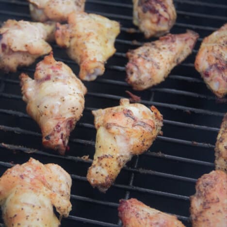 Close-up of cooked chicken wings still on the grill grates of the smoker.