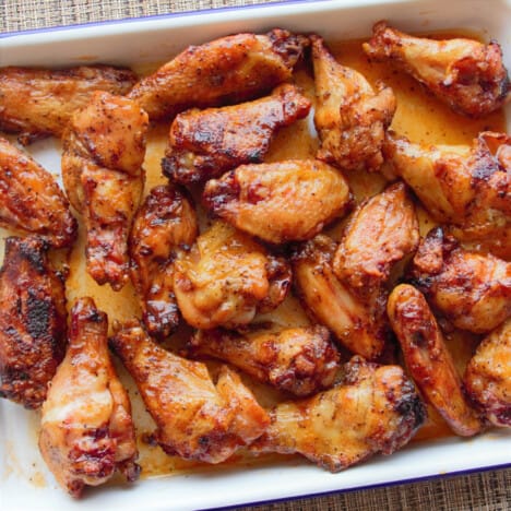 Cooked sriracha and honey chicken wings in a white serving tray ready to be served.