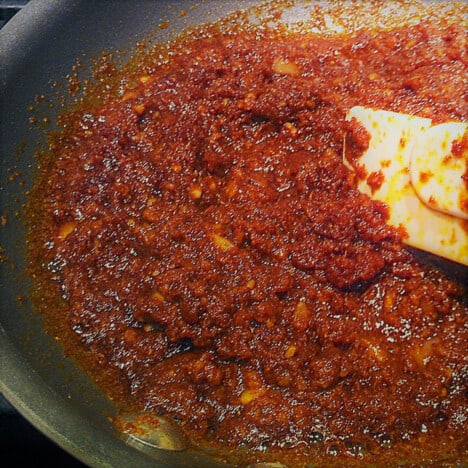 A fry pan with a curry base being lightly simmered and stirred.