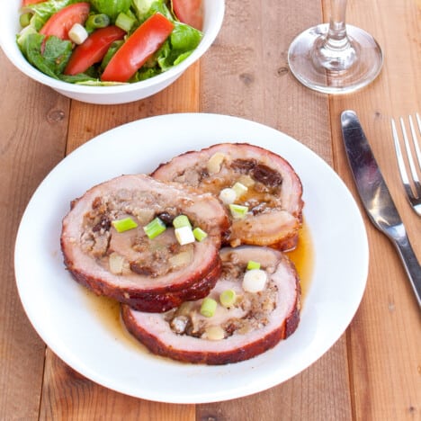 A white plate with slices of the spiralled apple and walnut filling in the pork loin.