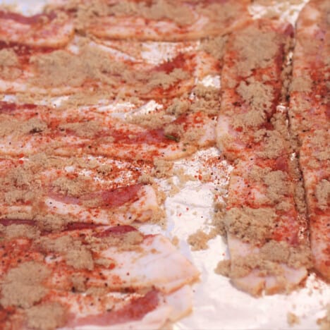 Strips of bacon laid out covered in brown sugar and cayenne pepper.