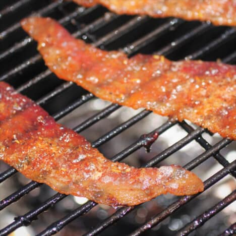 Close up of two strips of almost cooked bacon pig candy on a rack.