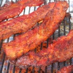 Cooked strips of bacon candy cooling over a foil covered bench.