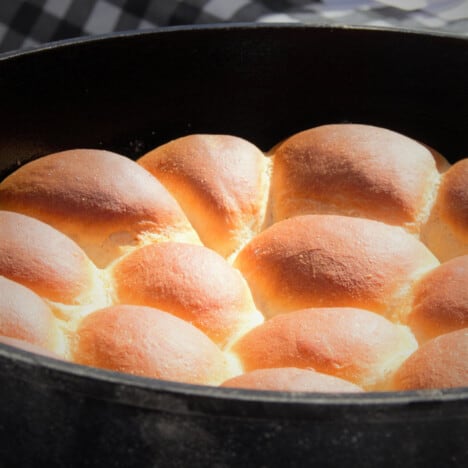 Close up of baked bread rolls with a brown top still in the Dutch oven.