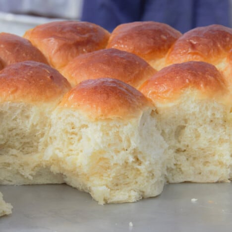 Baked batch bread rolls with some removed exposing the light dough texture inside.