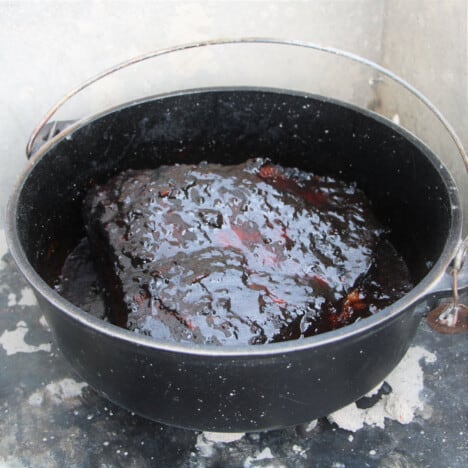 A Dutch oven with a glossy brisket in in.