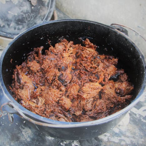 A Dutch oven filled with pulled brisket.