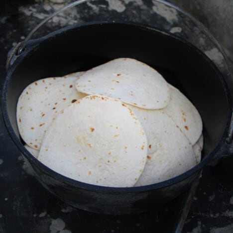 A Dutch oven filled with heated tortillas ready to be served.