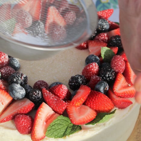 A sift dusting powdered sugar over the decorative fruits.