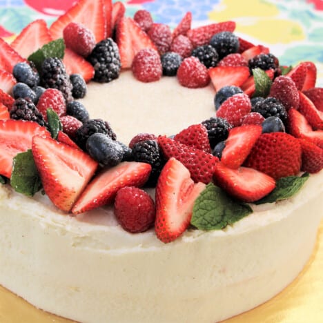 Close up of a ring of mixed berries with mint decorating the top of the cake.