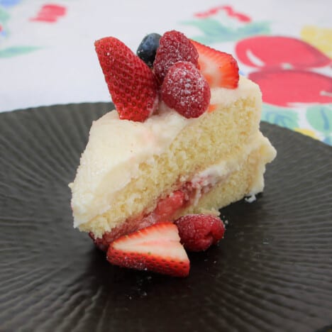 A slice of strawberry cake served on a black plate.