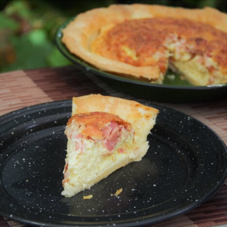 A single piece of bacon and egg pie served on a black camp plate.
