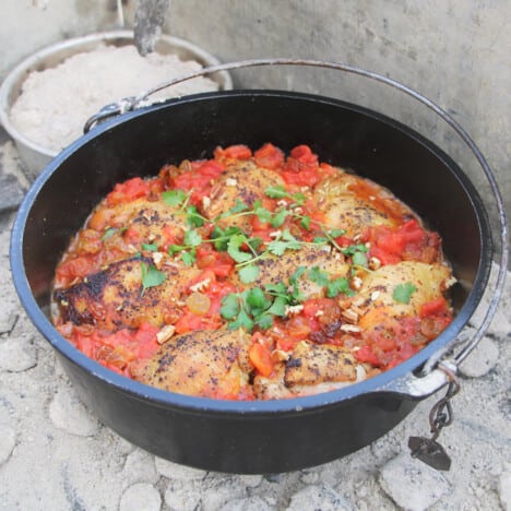 A Dutch oven filled with chicken thighs cooked in a tomato rice.