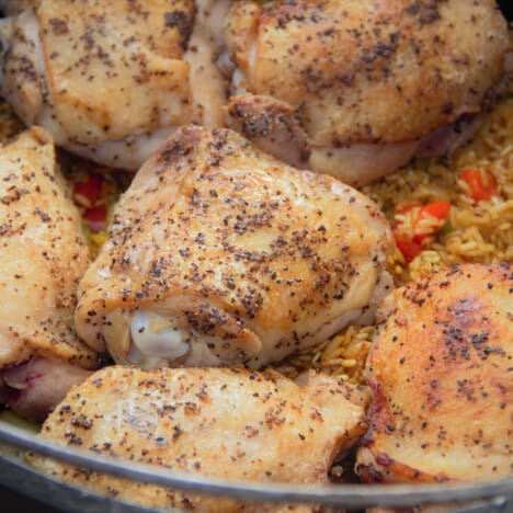 Close up of fried chicken sitting on seasoned rice ready to be baked.