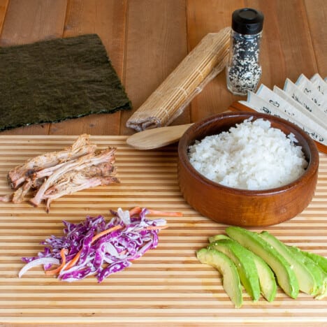 Ingredients to make pulled pork suhi laid out on a sushi mat.