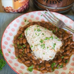 A piece of Alabama white chicken served on a layer of baked beans.