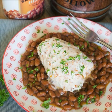 A piece of Alabama white chicken served on a layer of baked beans.